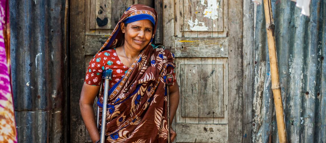 A woman with a crutch smiling at the camera