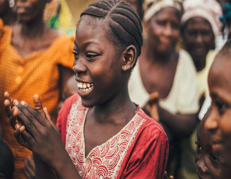 Woman in a crowd with her hands together and smiling