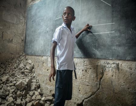 Young boy standing in front of blackboard