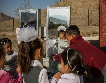 A group of young children washing their hands outside