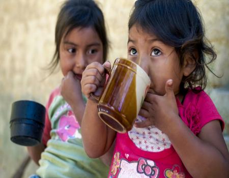 Two young girls drinking from cups