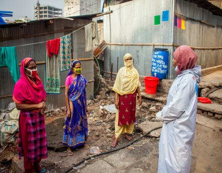 3 ladies with mask getting advised by PPE kit lady